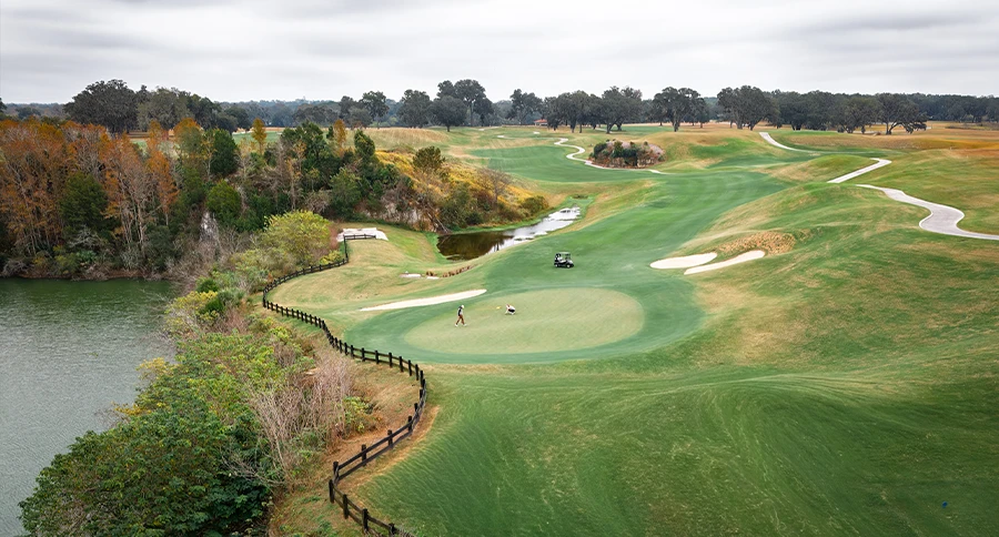 Aerial view of golfers playing a championship golf hole beside Iron Lake at The Club at Iron Lak