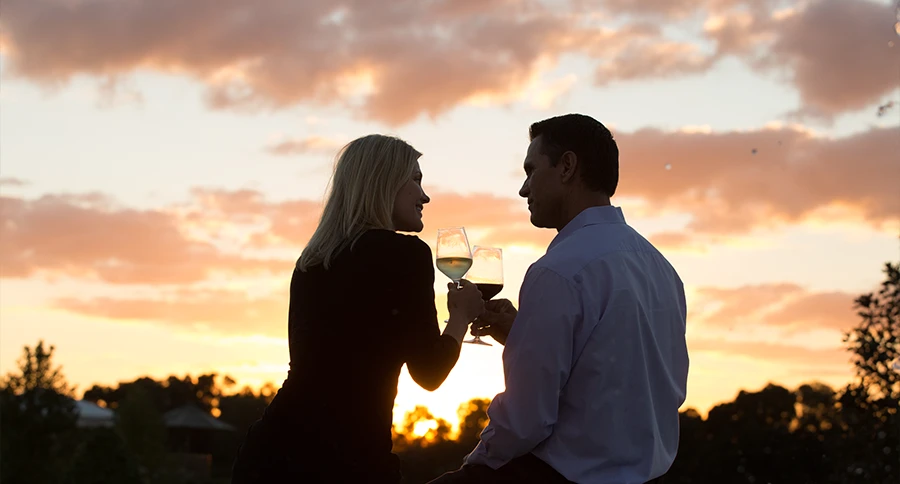 Two members enjoy wine together at sunset during a social gathering at The Club at Iron Lake.