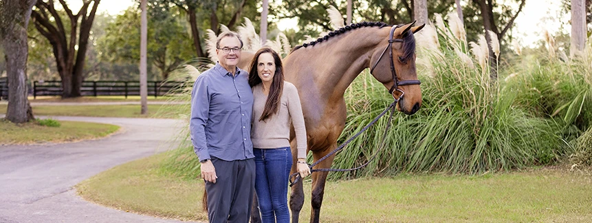 Craig and Elizabeth Phillips standing beside a horse in an Ocala equestrian setting.