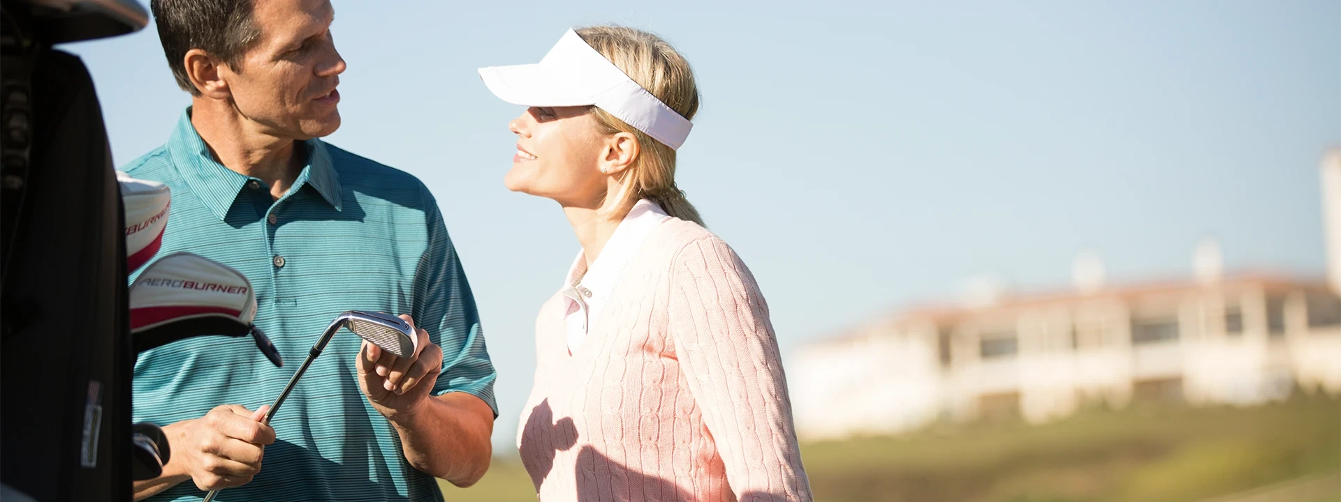 Two members discussing a golf club beside a golf cart at The Club at Iron Lake in Ocala, Florida.