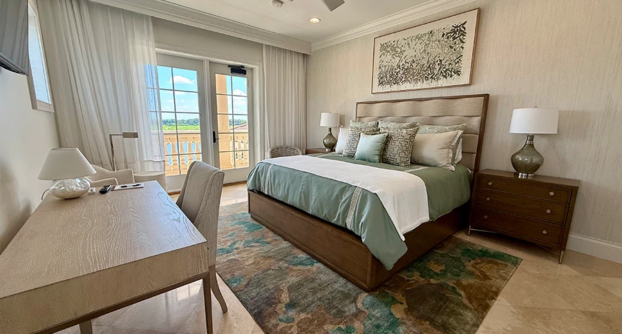 Guest bedroom at The Club at Iron Lake with a king bed, neutral furnishings, desk, television, and balcony doors.