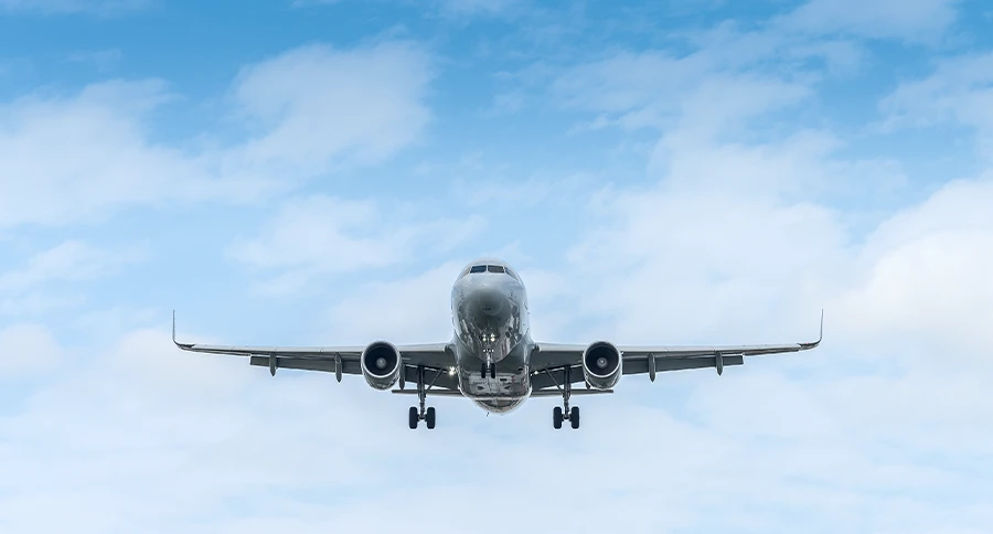 Commercial passenger airplane approaching for landing against a blue sky with scattered clouds.