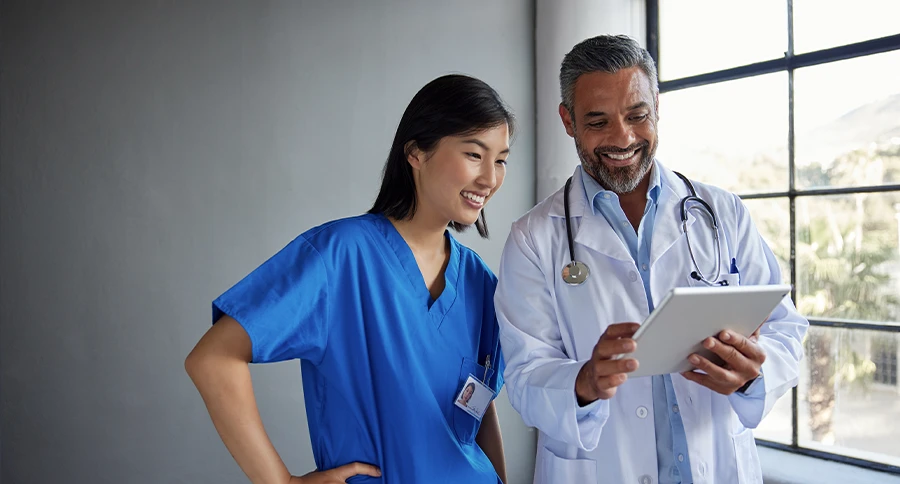 Doctor and healthcare professional reviewing information together on a tablet.