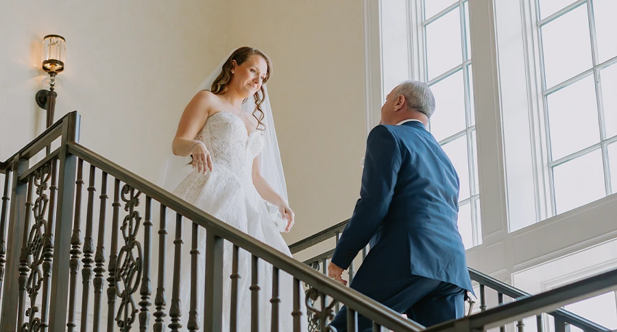 Bride greeting a man on an elegant staircase at The Club at Iron Lake.