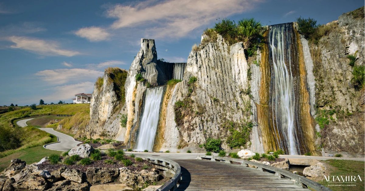 Dramatic limestone cliffs with cascading waterfalls frame a winding boardwalk path at Altamira Development Company's master-planned community.